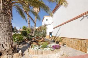 un jardin avec des palmiers et des fleurs à côté d'un bâtiment dans l'établissement Hostal Manolo, à Garrucha