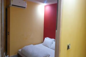 a small room with a bed and a red wall at OYO Hotel Eleven in Bhāgalpur