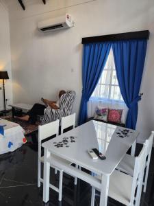 a person sitting in a chair in a living room with a white table at BERUNTUNG KE BARI RESORT @ PANTAI PENARIK in Kampong Bari Kechil