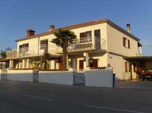 une maison blanche avec un palmier en face dans l'établissement Apartments Ljubica, à Rovinj