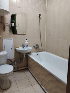 a bathroom with a tub and a sink and a toilet at Glinki 33 Apartments in Semey