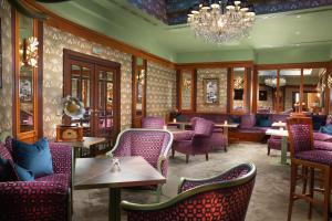 ein Restaurant mit lila Stühlen und Tischen sowie einem Kronleuchter in der Unterkunft Grand Hotel Bohemia in Prag