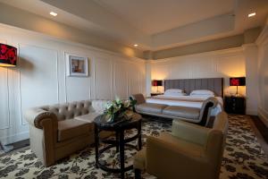 een slaapkamer met een bed en een bank en stoelen bij Crown Garden Hotel in Kota Bharu