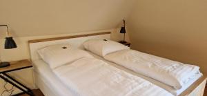 ein weißes Bett mit zwei Kissen darüber in der Unterkunft Lindenhof 1887 in Lunden