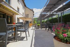 eine Außenterrasse mit Tischen, Stühlen und Blumen in der Unterkunft Hôtel Aurélia in Saint-Lary-Soulan