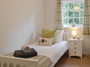 Un pequeño dormitorio con una cama blanca y una ventana en Nice Cottage In Gatehouse Of Fleet With 2 Bedrooms And Wifi en Gatehouse of Fleet
