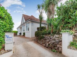 a white house with a stone wall and palm trees at Shoreline in Goodrington