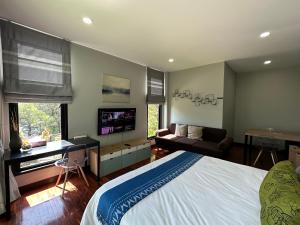 Schlafzimmer mit einem Bett, einem Schreibtisch und einem TV in der Unterkunft PomPom Home in Bangkok