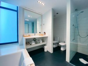 a bathroom with a tub and a sink and a toilet at Empordà Golf Resort in Torroella de Montgrí