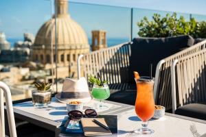 a table with two drinks on top of a balcony at The Embassy Valletta Hotel in Valletta