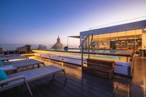 a rooftop deck with tables and a swimming pool at The Embassy Valletta Hotel in Valletta