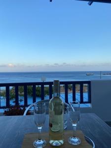 una botella de vino sentada en una mesa con dos copas en Ardani Bay Studios en Amoopi