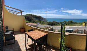 a balcony with a table and a view of the ocean at Torre Del Pozzo in S'archittu Cuglieri