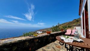 a table and chairs on a stone wall overlooking the ocean at Rincón de Mercedes in Fuencaliente de la Palma