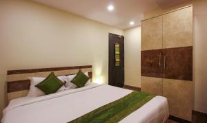 Treebo Trend Address Inn في حيدر أباد: غرفة نوم بسرير ابيض كبير مع مخدات خضراء