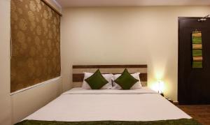 a bedroom with a large white bed with green pillows at Treebo Trend Address Inn in Hyderabad