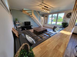 a living room with a brown couch and a staircase at La maison des vacances 8 personnes in Ghyvelde