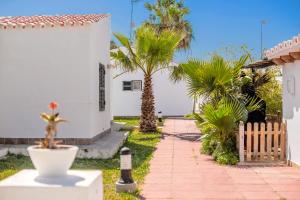 a white house with palm trees and a sidewalk at Son Xoriguer 14 in Son Xoriguer