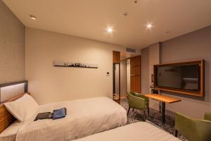 a hotel room with two beds and a flat screen tv at Via Inn Prime Osaka Kyobashi in Osaka