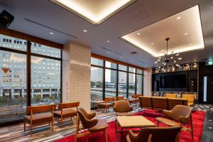 a lobby with tables and chairs and a large window at Via Inn Prime Osaka Kyobashi in Osaka