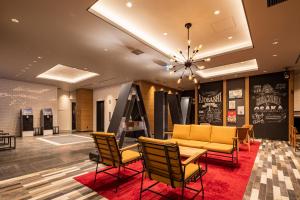 a lobby with chairs and a couch and a chandelier at Via Inn Prime Osaka Kyobashi in Osaka