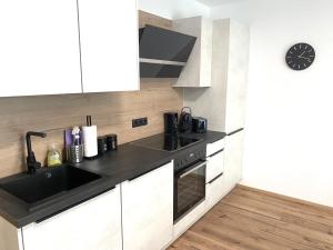 a kitchen with white cabinets and a black sink at Apartments Loim Lodge in Dürnstein