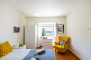 1 dormitorio con 1 cama y 1 silla amarilla en Ambassador River View Suites, en Lisboa