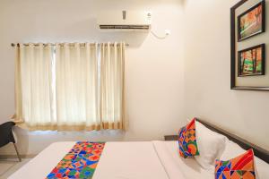 a bedroom with a bed and a window at FabHotel Archanil Apartment in Nagpur