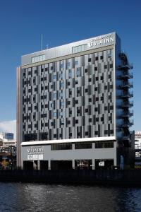 a large building with a sign on it next to the water at Via Inn Prime Osaka Kyobashi in Osaka