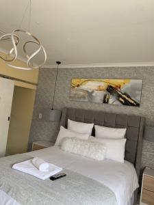 1 dormitorio con 1 cama blanca grande con lámpara de araña en Naliya Guest house en Ciudad del Cabo