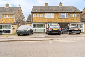 dos autos estacionados en un estacionamiento frente a una casa en Beaconsfield 4 Bedroom House in Quiet and a very Pleasant Area, Near London Luton Airport with Free Parking, Fast WiFi, Smart TV en Luton