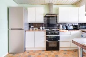 a white kitchen with white cabinets and appliances at Beaconsfield 4 Bedroom House in Quiet and a very Pleasant Area, Near London Luton Airport with Free Parking, Fast WiFi, Smart TV in Luton