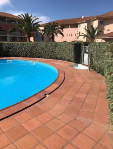 una piscina con passerella in mattoni accanto a un edificio di Studio Cala Sognu Moriani residence a San-Nicolao