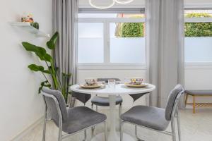 a white dining room with a white table and chairs at Top located 50m from beach in Caorle
