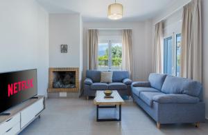 a living room with two blue couches and a tv at Lyrids Apartments in Episkopí- Rethimno
