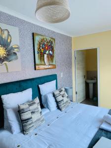 Un dormitorio con una cama blanca con almohadas y una pintura en Naliya Guest house en Ciudad del Cabo