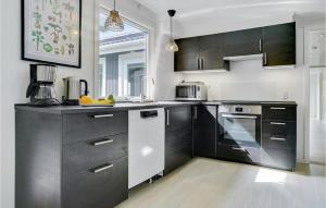 a kitchen with black and white cabinets and appliances at Amazing Home In Væggerløse With Sauna in Marielyst