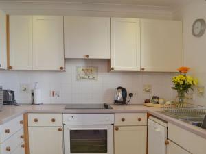 a kitchen with white cabinets and a sink at Oaktree Cottage in Stoke Gabriel