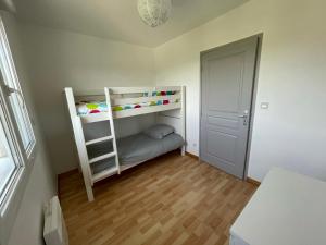a small room with two bunk beds and a door at Gîte de Vacances Maison 6 personnes - Clairvaux les Lacs, Jura in Clairvaux-les-Lacs
