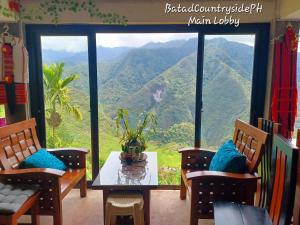 a room with a table and chairs and a view of a mountain at Batad Countryside in Banaue