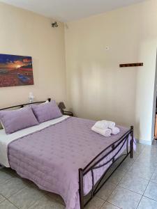 1 dormitorio con 1 cama grande con sábanas y toallas púrpuras en Kouremenos Beach Apartments, en Palaikastro