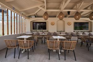 a restaurant with tables and chairs in a room with windows at Mila Malia Studios Hotel in Malia