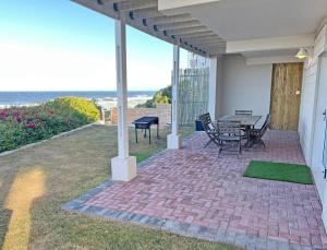 a patio with a table and chairs and the ocean at SEEMEEU in Jeffreys Bay