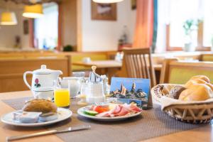 einen Tisch mit Teller mit Lebensmitteln und einen Korb mit Brot in der Unterkunft Hotel Pension Barbara in Sankt Martin am Tennengebirge