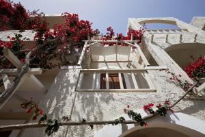 a window on a white building with red flowers at Mila Malia Studios Hotel in Malia