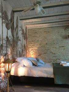 a bed in a room with a brick wall at Au Domaine du Petit Cercoux in Saint-Saturnin-du-Bois