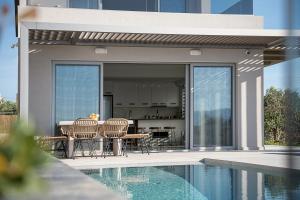 a patio with a table and chairs next to a pool at Fivi Luxury Villa, with Heated Pool & SeaViews, By ThinkVilla in Tavronitis