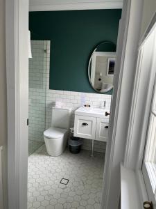 a bathroom with a toilet and a green wall at Dormie House in Moss Vale