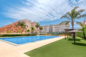 a swimming pool with palm trees and a building at Lopimar Exclusivo in Canet de Berenguer