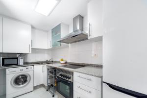 eine Küche mit weißen Schränken, einer Waschmaschine und einem Trockner in der Unterkunft Lopimar Exclusivo in Canet d'en Berenguer